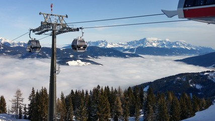 Ski Lift above Clouds between snow-topped mountains 