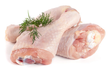 Three raw chicken drumsticks with a sprig of dill isolated on white background