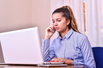 The girl works on a laptop, tablet and phone in the office