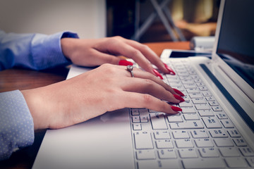 The girl works on a laptop, tablet and phone in the office