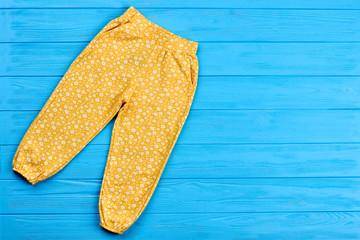 Colored trousers for baby-girl. Top view of baby girl summer pants and blue copy space. Fashionable clothing for kids.