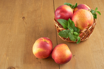 peaches in a wicker basket on wooden table with blurred background