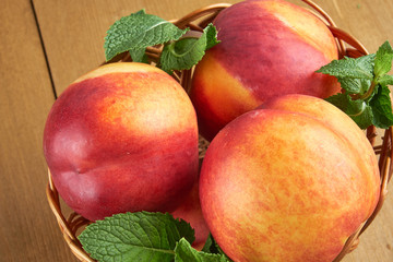 peaches in a wicker basket on wooden table with blurred background