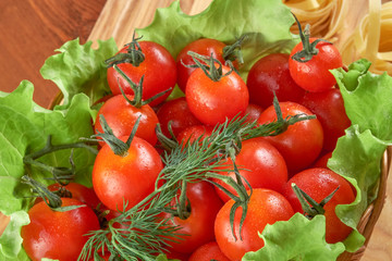 Fototapeta na wymiar Tomatoes in a wicker basket and green salad leaves