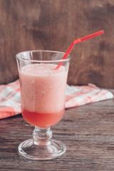 Smoothies of melon and watermelon in a glass on a wooden table.