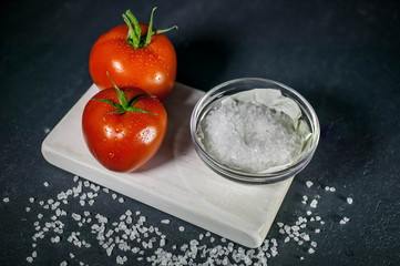 Tomatoes and salt on a dark background. Low-key lighting