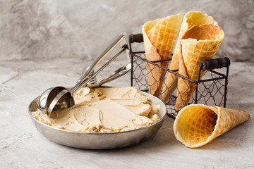 Caramel ice cream and waffle cones on stone table. Space for text