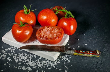Tomatoes and salt on a dark background. Low-key lighting