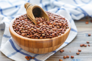 Wooden scoop in bowl with lentils.
