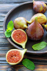 Fresh figs and mint leaves on a wooden platter.