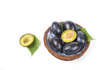 Plums in the wooden basket on the white background