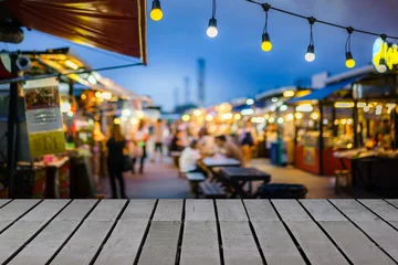 Draagtas Image of wooden table in front of decorative outdoor string lights bulb in night market with blur people, Festival and holiday concepts, can used for display or montage your products. © sommart
