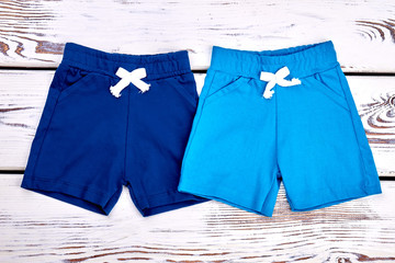 Collection of new shorts for baby boys. Toddler boy set of colored shorts on old wooden background....