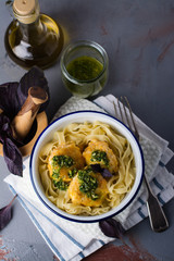 Fish balls with tagliatelle pasta and green pesto sauce on stone table. Space for text
