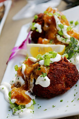 Sour Cream and Chive Topped Crab Cakes with Sliced Lemon and Plated With An Orchid  