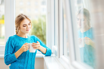 Young girl drinks coffee with milk and reflects. The concept of lifestyle, autumn and comfort.