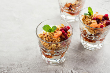 Layered dessert with granola, apple and red bilberry compote, cream