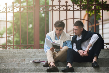 Self-education for two young men. Modern street style. Break in University outdoors, reading concept