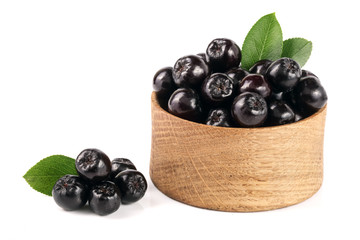 Chokeberry with leaf in wooden bowl isolated on white background. Black aronia berries