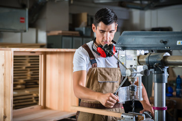 Cabinet maker working on power drill in his wood workshop