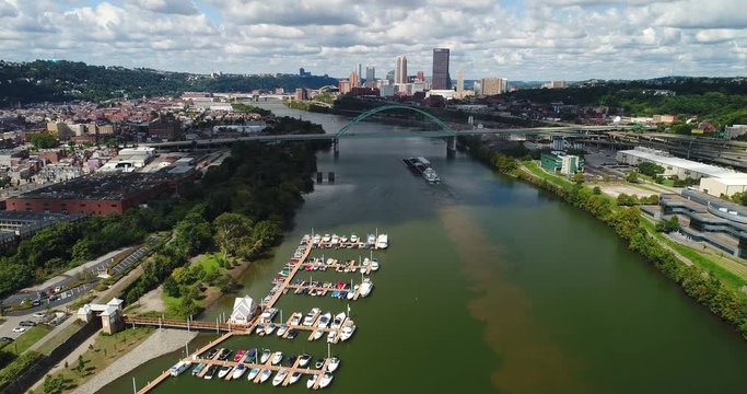 A high angle reverse moving aerial establishing shot of a marina on the Monongahela River with the Pittsburgh skyline in the distance.  	