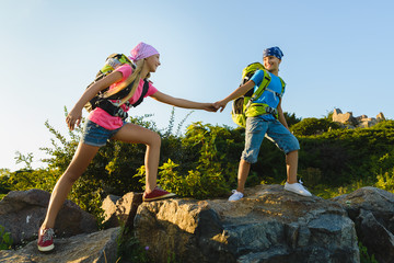 Girl and boy with backpacks in hills. Adventure, travel, tourism concept
