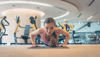 Woman doing push-up in sport gym for better fitness