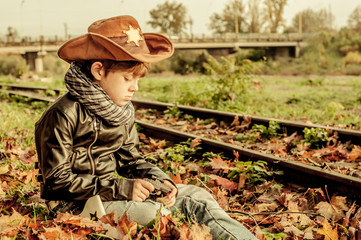 Boy in sheriff costume sitting near rails