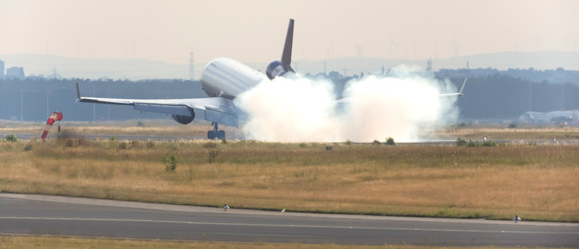 airplane landing at an runway with tire smoke cloud