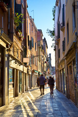 Narrow street with walking tourists in Venice, Italy