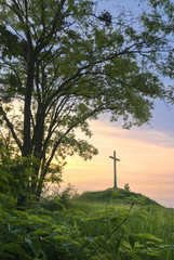 Cross on a hill during sunset.