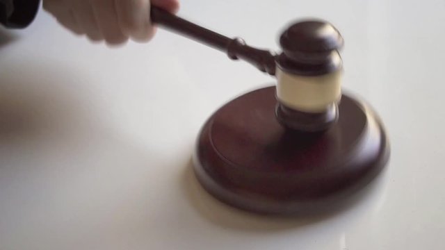 Gavel pounds on block in slow motion.