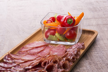 Set of meat delicatessen, tomatoes and peppers on a wooden table.