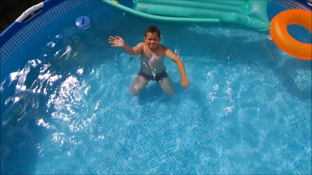 Little Boy Swimming In Pool on orange inflatable rubber ring.