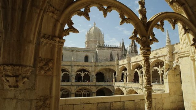 Beautiful reticulated vaulting on courtyard or cloisters of Hieronymites Monastery, Mosteiro dos Jeronimos, famous Lisbon landmark in Belem district and Unesco Heritage. Church dome on background.