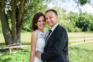 likable and pretty wedding couple stay and hugging in the garden by the tree