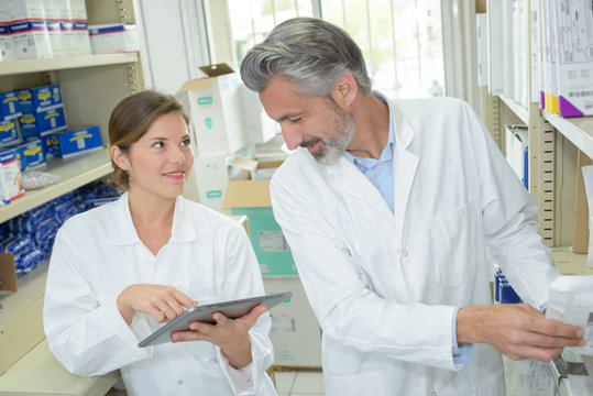 woman pointing at laptop screen when talking to pharmacist