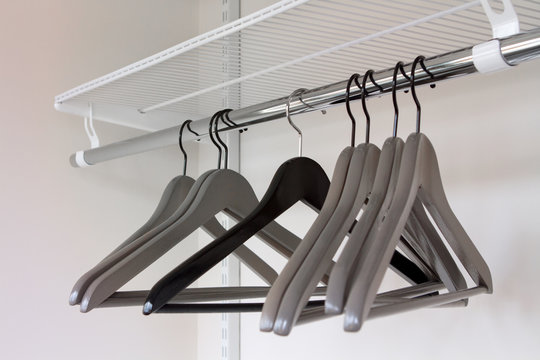 Clothes grey hangers in empty wardrobe, closeup