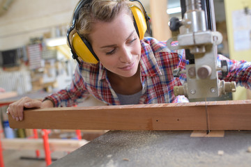 female carpenter cutting wood with an electrical jigsaw
