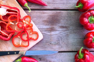 Vegetables red sweet bell peppers and hot chili on old wooden table.