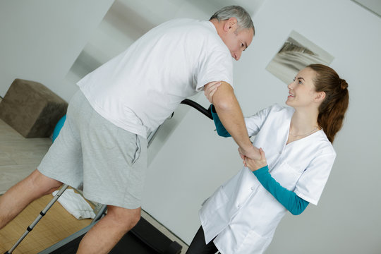 female physiotherapist standing by patient walking between paral