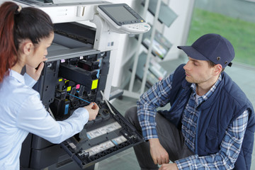 engineer and worker trying to repair the office printer
