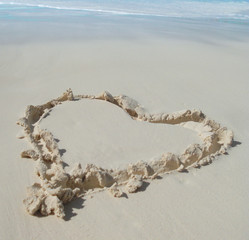 In Sand gezeichnetes Herz an einem Sandstrand in der Karibik
