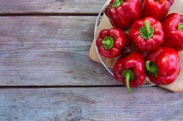 Fresh red sweet bell peppers on old wooden table.