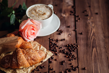 Coffee cup and coffee beans , croissant on brown wooden table