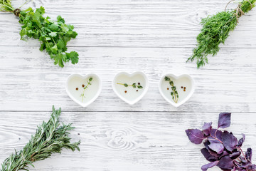 home cooking with fresh greenery and organic oil on light wooden table background top view