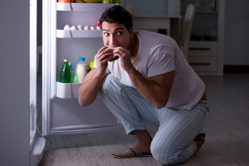 Man at the fridge eating at night