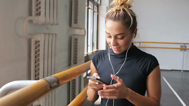 A ballerina uses a smartphone in a large training hall