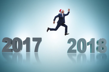 Businessman in santa hat jumping from 2017 to 2018