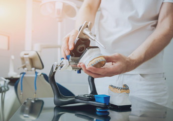Dental technician working with articulator in dental lab